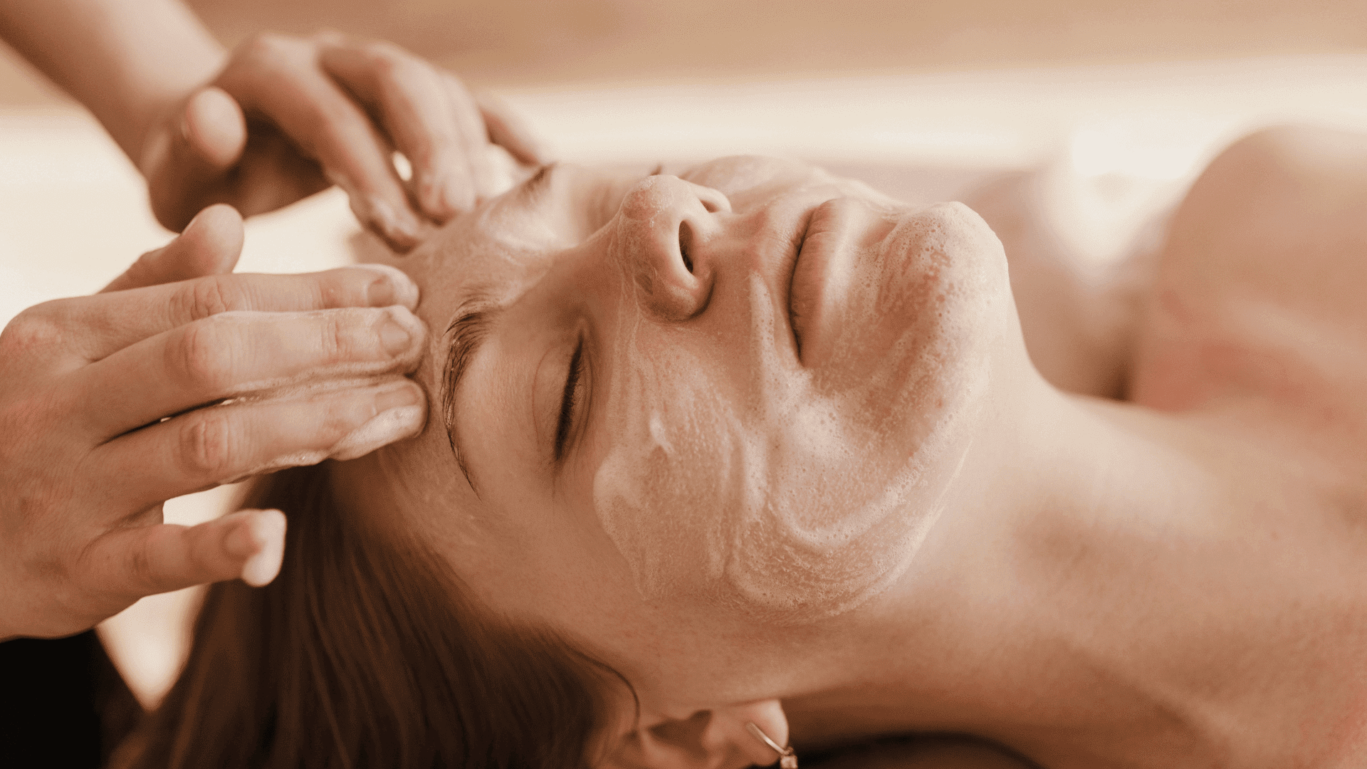 Person receiving a relaxing facial massage with a skin treatment mask applied.