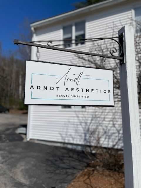 Arndt Aesthetics sign outside a white building under a clear blue sky.