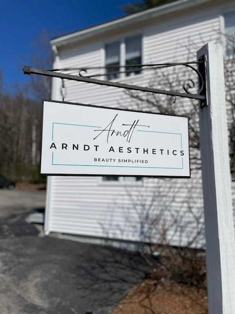 Arndt Aesthetics sign outside a white building under a clear blue sky.